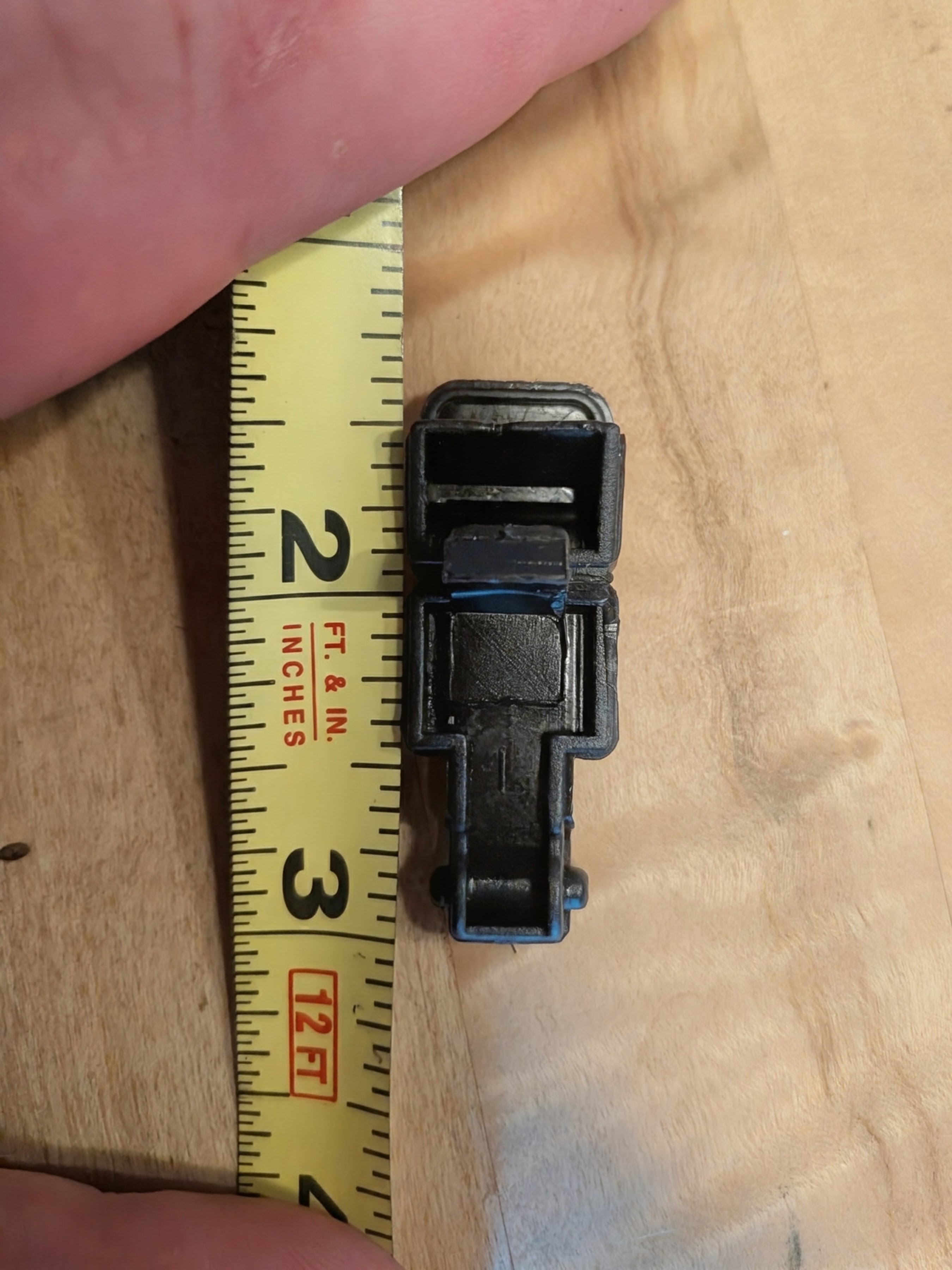 A Jeep latch beside a tape measure, photographed as a reference for the replacement part